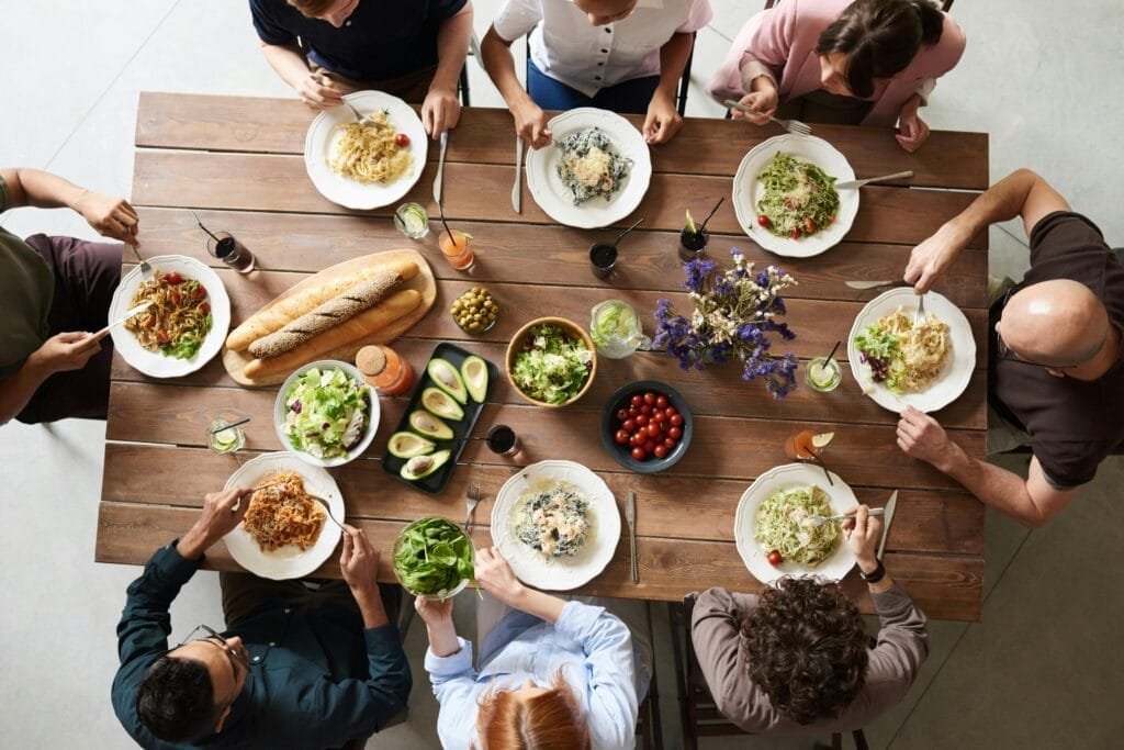 A diverse group of adults enjoying a shared meal indoors, viewed from above.